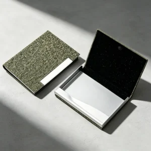 Minimalist eco-friendly business card holder made from upcycled green tea husks, displaying unique natural bio-granule textures on a micro-cement surface under sharp morning light. Perfect as a high-end sustainable corporate gift.