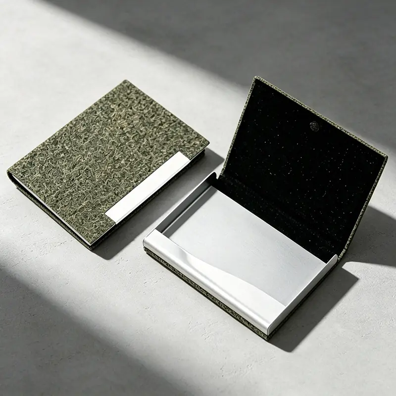 Minimalist eco-friendly business card holder made from upcycled green tea husks, displaying unique natural bio-granule textures on a micro-cement surface under sharp morning light. Perfect as a high-end sustainable corporate gift.